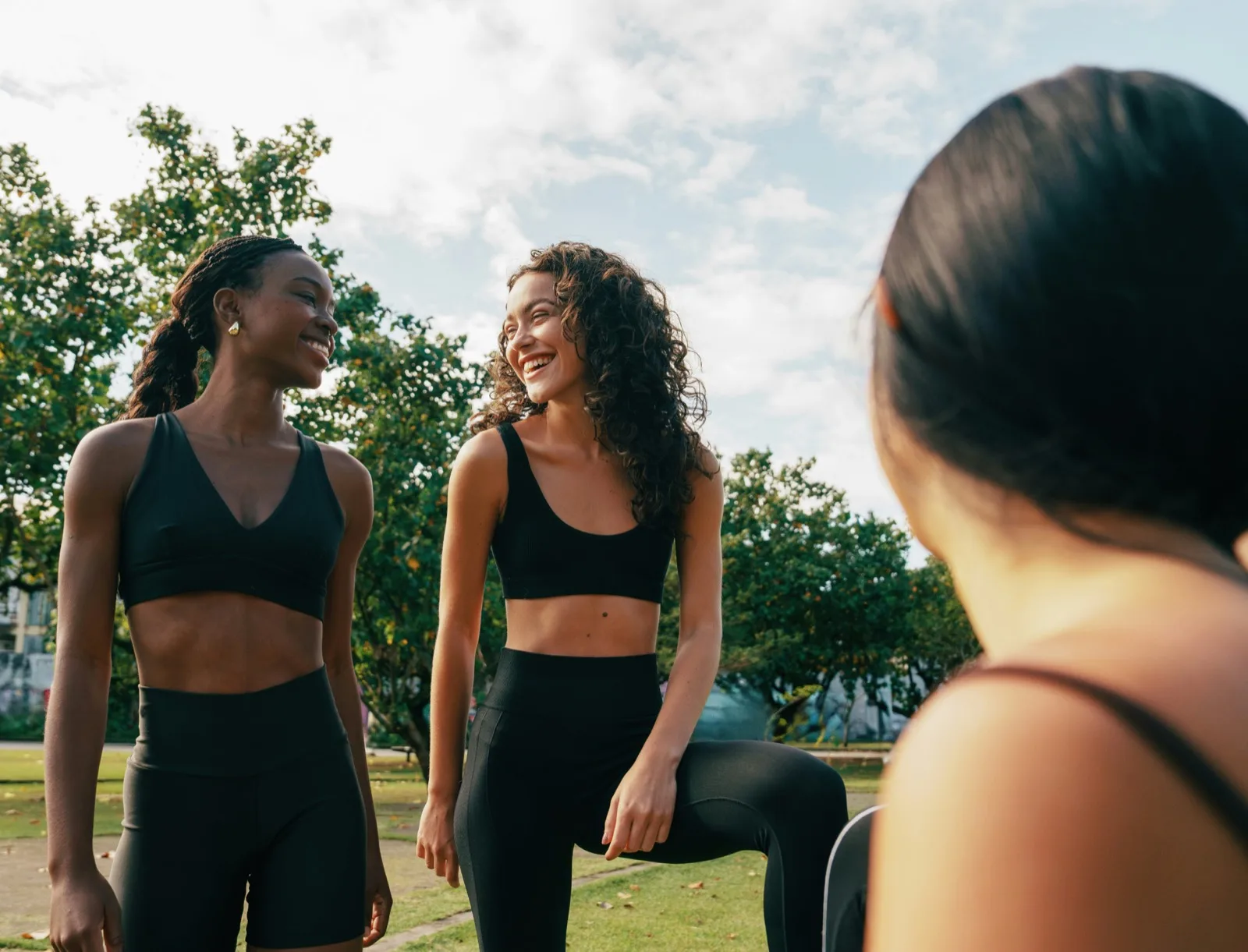 Three women outdoors sharing a moment after activity