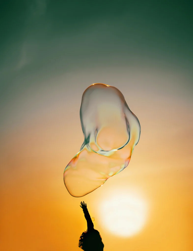A person reaching toward bubbles in sunlight
