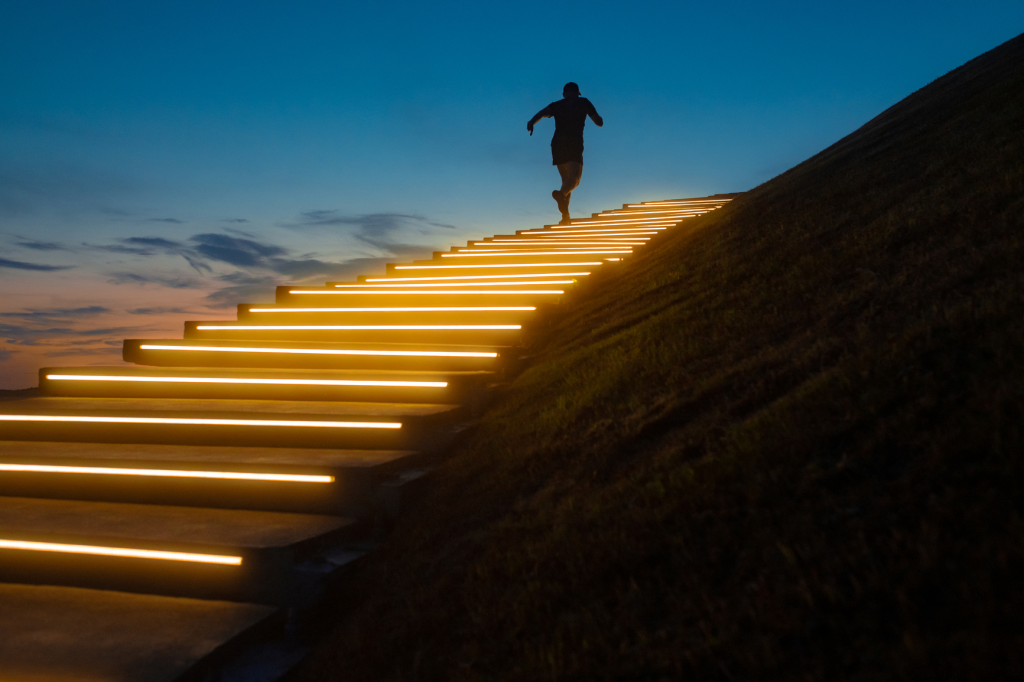 A person running up a glowing staircase at sunset